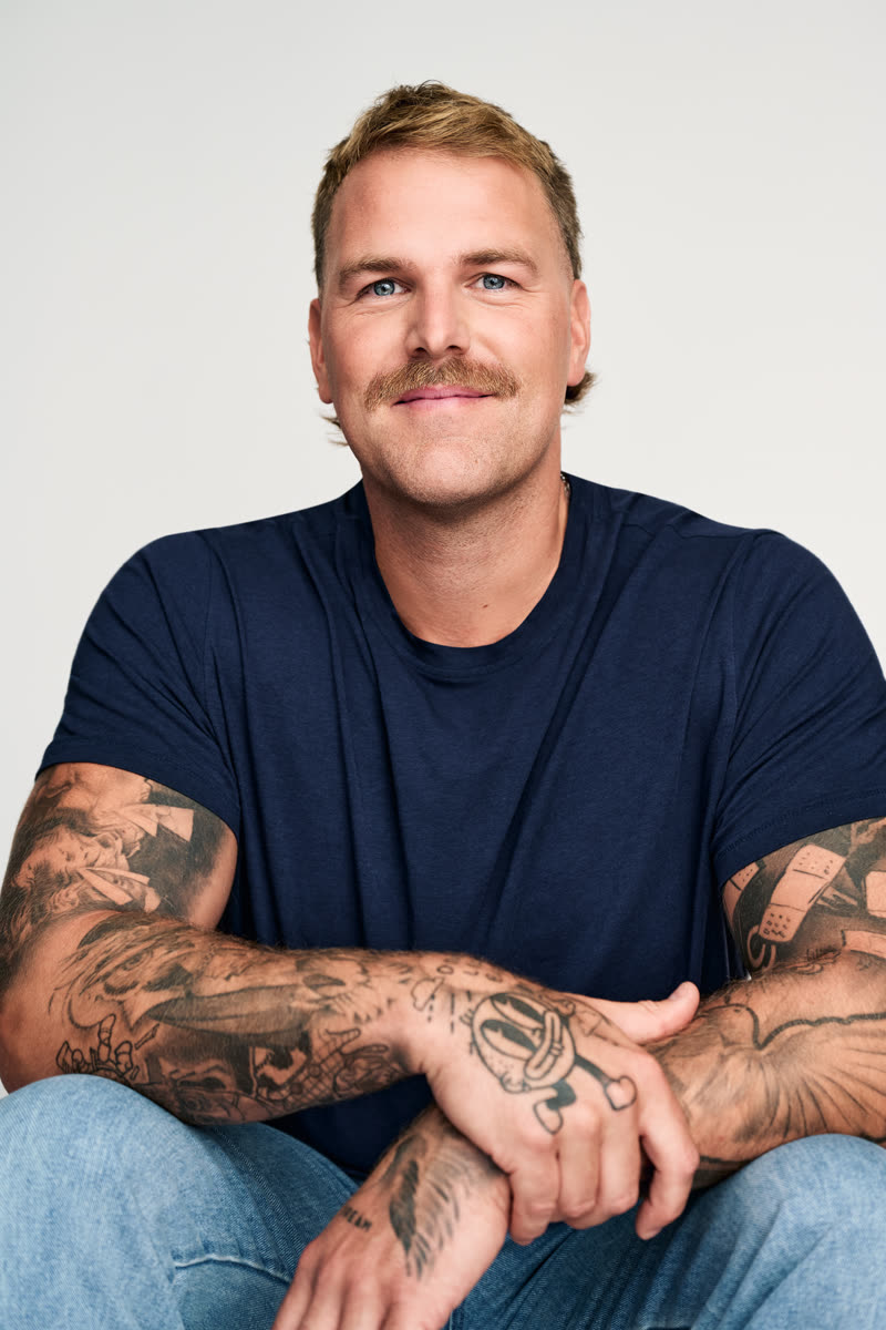 Portrait de studio, t-shirt marine, bras posés sur les genoux